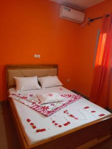 a bed with flowers on it with an orange wall at NPANGOU APPART in Kribi