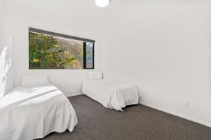 2 camas en una habitación blanca con ventana en Mountain Escape - Cromwell Downstairs Apartment, en Cromwell