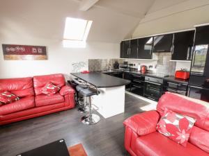 a living room with a red couch and a kitchen at Derrybeg Apartment in Doirí Beaga +5 photos