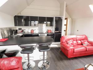 a living room with a red couch and a kitchen at Derrybeg Apartment in Doirí Beaga