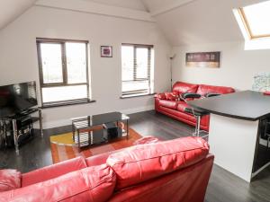 a living room with red leather couches and a table at Derrybeg Apartment in Doirí Beaga