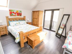 a bedroom with a wooden bed with a wooden floor at Derrybeg Apartment in Doirí Beaga