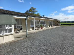 un edificio con un patio con mesas y sillas en Tower Road Motel, en Matamata