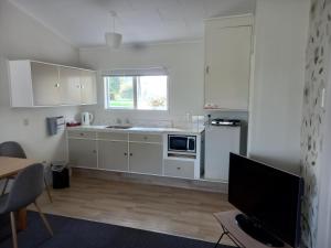 a kitchen with white cabinets and a tv in it at Tower Road Motel in Matamata