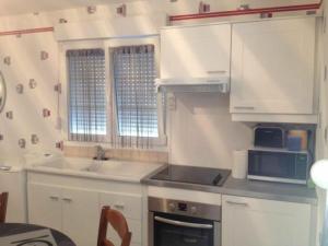 eine Küche mit weißen Schränken, einer Spüle und einer Mikrowelle in der Unterkunft Gîte Étain, 2 pièces, 2 personnes - FR-1-585-3 in Étain