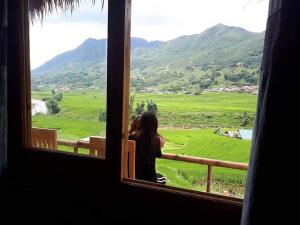 a woman looking out a window at a green field at SaPa Farmer House in Sapa