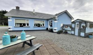 a blue house with a picnic table in front of it at Clifden Wildflower Cottage - Clifden Countryside Lettings in Clifden