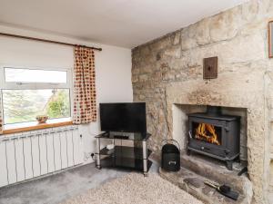 a living room with a stone fireplace and a television at Silver Hill Cottage in Harrogate