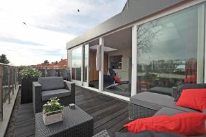 een balkon met een bank en stoelen op een dak bij Aan't Kanaal in Harlingen