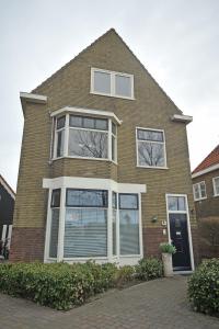 una casa de ladrillo marrón con ventanas blancas. en Aan't Kanaal, en Harlingen