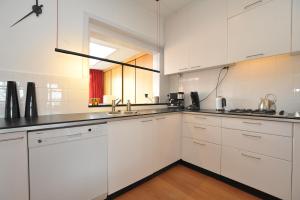 una cocina blanca con armarios blancos y fregadero en Aan't Kanaal, en Harlingen