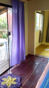 Habitación con cortina púrpura y suelo de madera. en Chalé aconchegante em estância climática, en Santo Antônio do Leite
