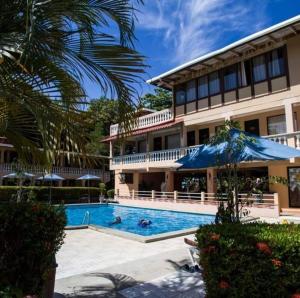 a hotel with a swimming pool in front of a building at House of the Macaws in Tarcoles