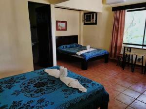 a hotel room with two beds with towels on them at House of the Macaws in Tarcoles
