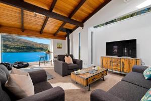 a living room with a couch and a tv at Queenstown Lakefront Dream 4 Bed in Queenstown