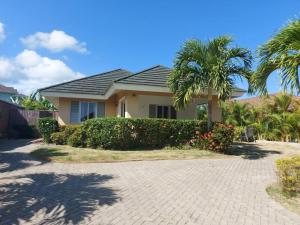 a house with a palm tree and a brick driveway at PALMS ESCAPE - 3 BEDROOM VACATION HOME in Richmond