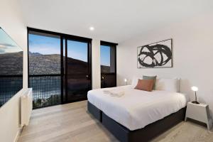a bedroom with a large bed and large windows at The Bunker Bravo A in Queenstown