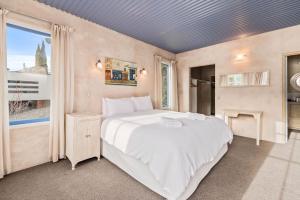 a bedroom with a large white bed and a window at Sunny Lakeview Villa in Queenstown