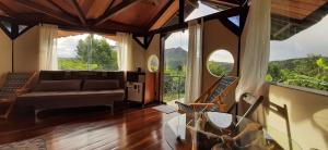 uma sala de estar com um sofá e janelas grandes em Flor da Vida _ Honeymoon suite - Vale do Capao em Palmeiras