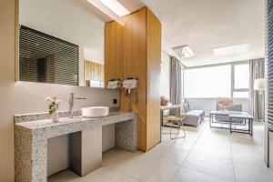 a bathroom with a sink and a living room at Hotel The Designers Hongdae in Seoul
