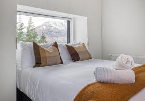 ein Schlafzimmer mit einem weißen Bett mit Kissen und einem Fenster in der Unterkunft The Rata Luxury Penthouse in Queenstown