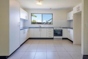 a large kitchen with white cabinets and a window at 26 Rumbalara Avenue Rainbow Beach Aircon Walk To Beach in Rainbow Beach
