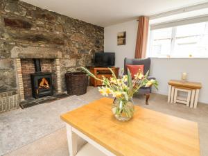 a living room with a fireplace and a vase of flowers on a table at Storkery Cottage in Aberdeen