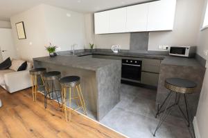 a kitchen with a counter and four bar stools at The Poppy Fields Abode in Rhyl