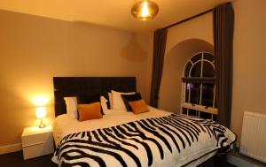a bedroom with a zebra print bed with a large mirror at The Poppy Fields Abode in Rhyl