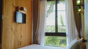 a bedroom with a bed and a window with a television at Cabins by Eco Hotel Tagaytay in Tagaytay