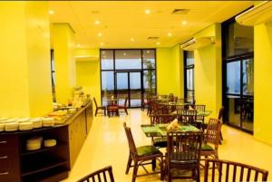 a restaurant with tables and chairs and yellow walls at Tropical Executive Flat Vista da Orla in Manaus