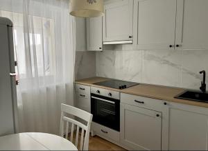 a kitchen with white cabinets and a table and a stove at N-J Apartament in Narva-Jõesuu