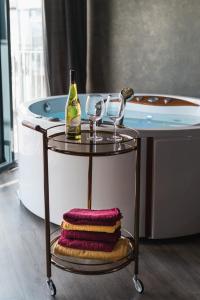 a bottle of wine and two glasses on a table next to a tub at Exclusive Jacuzzi Apartaments Klaipėda in Aukštkiemiai