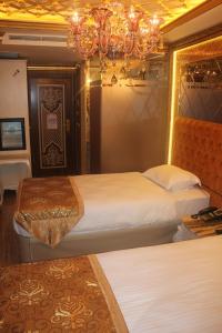 イスタンブールにあるLaleli Blue Marmaray Hotelのベッド2台とシャンデリアが備わるホテルルームです。