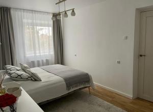 a white bedroom with a bed and a window at N-J APARTANENT in Narva-Jõesuu