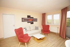 ein Wohnzimmer mit roten Stühlen und einer weißen Couch in der Unterkunft strandnah mit Balkon, gratis Nutzung vom AHOI Erlebnisbad und Sauna in Sellin - Strandhaus Mönchgut FeWo12 in Lobbe