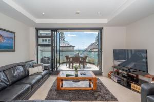 a living room with a couch and a tv and a table at ELEVEN APARTMENT in Tauranga