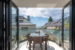 a dining room with a table and chairs on a balcony at ELEVEN APARTMENT in Tauranga