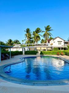 a swimming pool in front of a house with palm trees at Catsen Bungalows & Pool Phan Thiet in Phan Thiet
