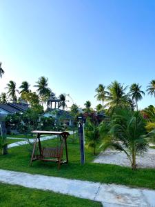 a park with a bench and a table and palm trees at Catsen Bungalows & Pool Phan Thiet in Phan Thiet