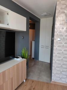 een keuken met witte kasten en een flatscreen-tv bij Apartament Nadmorski in Kołobrzeg