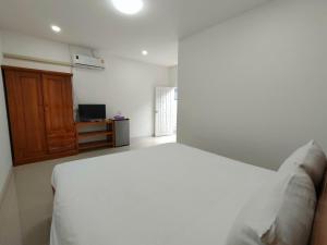 - une chambre avec un lit blanc et une armoire en bois dans l'établissement King Fa House, à Mae Sot