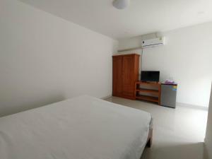 ein Schlafzimmer mit einem weißen Bett und einem kleinen Schrank in der Unterkunft King Fa House in Mae Sot