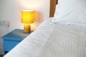 a bed with a yellow lamp on a blue nightstand at Northlight, Port Isaac Bay Holidays in Port Isaac