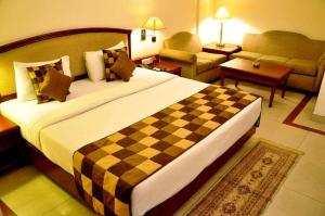 a hotel room with a large bed and a living room at Hotel Jewel Palace in New Delhi