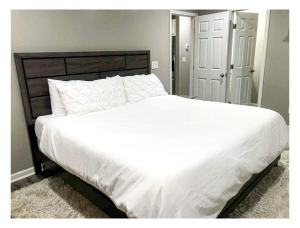 uma cama grande com lençóis brancos e almofadas num quarto em Lovely 3BR 3BA Home minutes from Airport/Downtown Atlanta em Atlanta