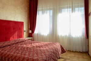 una camera con un letto rosso e due finestre di Hotel Fiordigigli ad Assergi