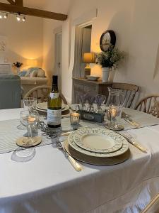 a white table with a bottle of wine on it at Hawthorn Cottage at Waingrove Farm in Fulstow