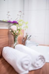 uma toalha sentada no balcão da casa de banho com um vaso de flores em Weingut Kernwein em Seinsheim