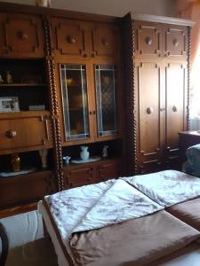 a bedroom with a bed and some wooden cabinets at Karkusz Apartman in Abádszalók